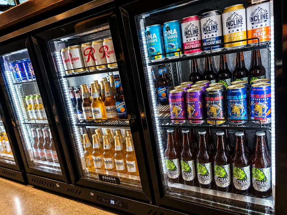 Three glass-door fridges stocked with beer and cider.